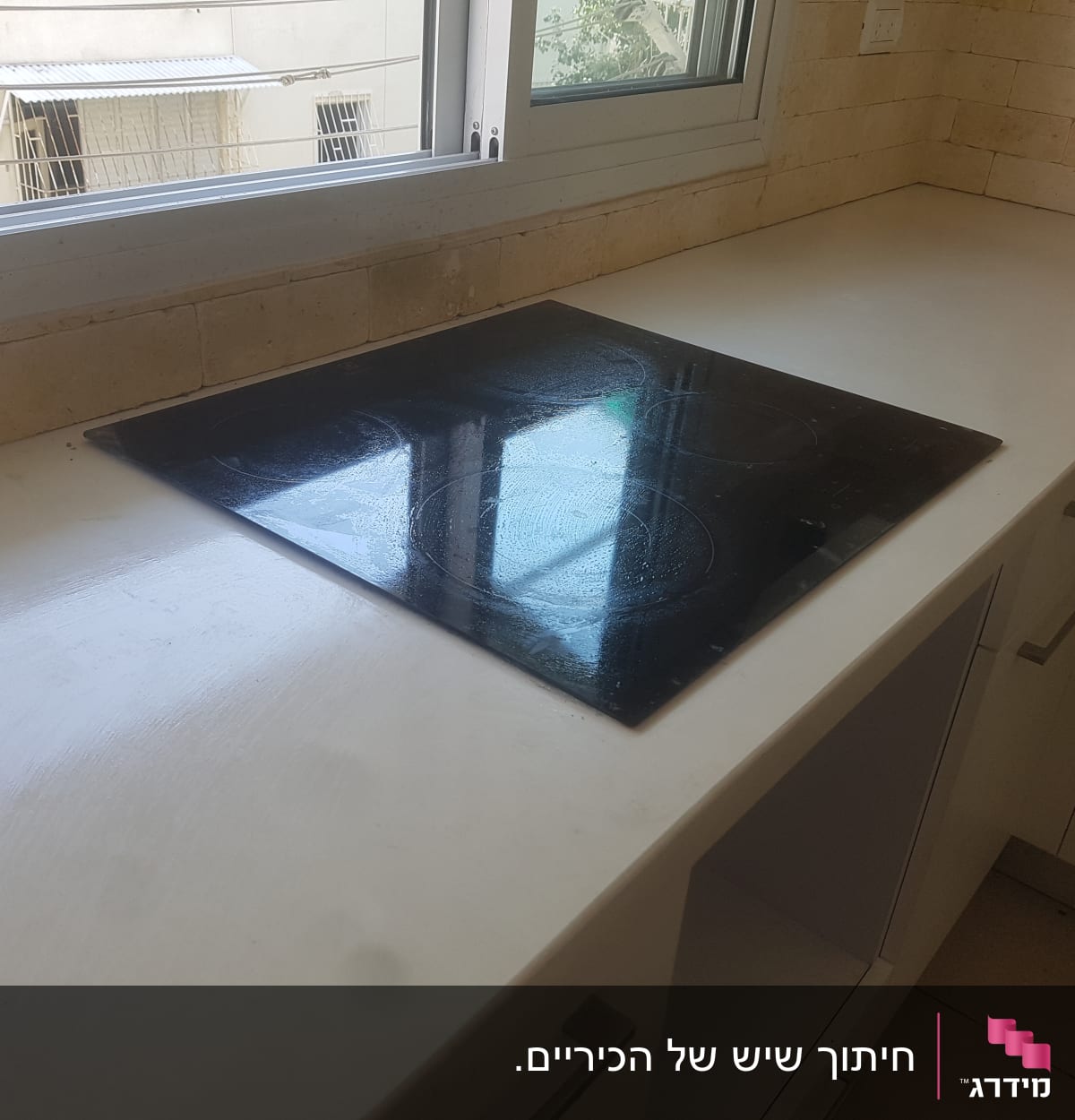 משטח שיש לבן עם כיריים שחורות במטבח
